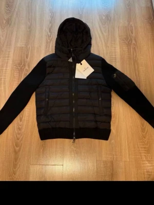 Svart cardiganjacka från Moncler - Snygg svart cardiganjacka från Moncler med vadderad front och huva. Helt ny aldrig använd stolek S vet ej om den e äkta 