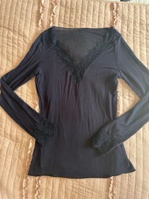 Intimissmi - Snygg mörkblå långärmad topp med djup V-ringning och spetsdetaljer vid halsringning och ärmslut. Tunn och stretchig i materialet, perfekt för lager på lager eller som statement-plagg. Ingen synlig logga eller märke. PRIS KAN DISKUTERAS OCH KAN ÄVEN BYTA MOT EN ANNAN FÄRG