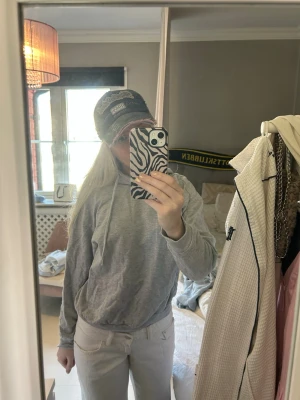 Ljusgrå hoodie med huva - En basic ljusgrå hoodie med huva och dragsnören. Hoodien har en avslappnad passform och är tillverkad i mjukt bomullsmaterial. Perfekt för en chill och enkel stil. Inga synliga loggor eller tryck på framsidan.