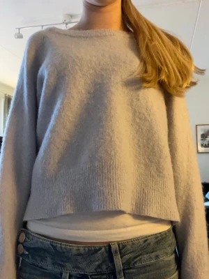 Ljuslila croppad stickad tröja - Snygg ljusblå stickad tröja med croppad passform och rund hals. Tröjan har långa ärmar och ribbstickad kant nedtill. Tvättad så att den blev lite mindre men är fof likadan som innan men lite mindre.