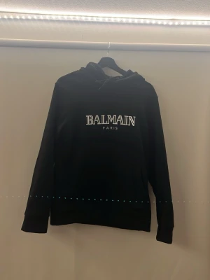 Svart balmain paris hoodie  - Säljer min svarta balmain Paris hoodie då jag inte har användning av den längre, det är storlek S och passar dig som är från 170-180cm, på sista bilden har jag på mig den och jag är 180cm, väldigt väldigt bekväm och varm hoodie! Inga defekter eller liknande!