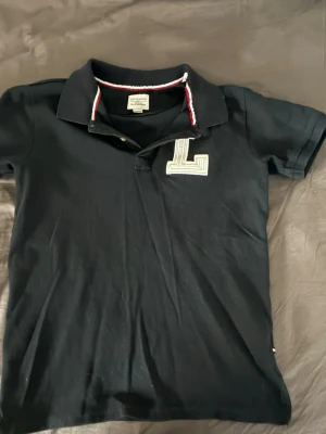 pikétröja Lindbergh  - Snygg marinblå pikétröja från Lindbergh som har varit med mig ett tag. Har inte använt den på ett tag nu så kände de va dags att sälja.