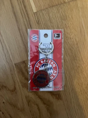 FC Bayern München nyckelring - Säljer en officiell FC Bayern München nyckelring i metall med klubbens klassiska röd, vit och blå logga. Perfekt accessoar för dig som älskar fotboll och vill visa ditt stöd för laget. Nyckelringen har rund form och är enkel att fästa på nycklar eller väska.