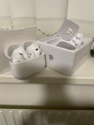 Apple AirPods Pro med laddningsetui - Säljer ett par vita Apple AirPods Pro med trådlöst laddningsetui. Hörlurarna har en stilren och kompakt design i blank plast och levereras i originalförpackning. Perfekta för dig som vill ha brusreducering och grymt ljud i ett smidigt format.