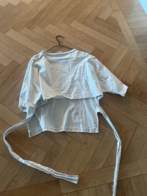 Vit omlottopp med knytband - Snygg vit omlottopp med långa knytband där bak, är i ny skick har inte använt mycket