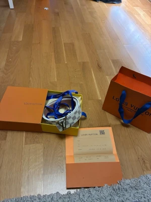 Rutigt bälte - Säljer ett snyggt rutig bälte från  i vitt och grått. Bältet har klassisk -logga på spännet och levereras med originalförpackning och påse. Perfekt accessoar för att lyfta din outfit.