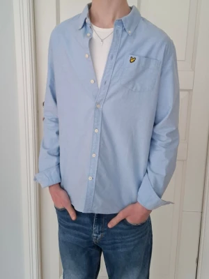 Lyle & Scott skjorta - Säljer en ljusblå skjorta från Lyle & Scott. Modellen är 173cm lång och skjortan sitter ungefär som en storlek 170cm. Riktigt snygg skjorta i mcyket bra skick, som passar till både vardag och finare tillfällen. Ifall du har fler frågor skriv gärna!👍