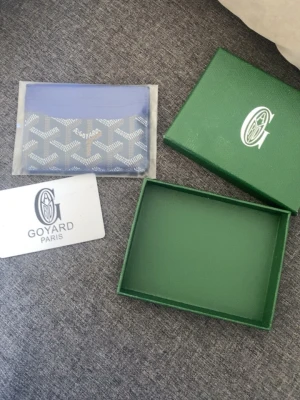 Blå Go4ard korthållare med mönster - Säljer en blå korthållare från Go4ard med deras ikoniska vita och grå mönster. Plånboken har flera kortfack och levereras med original ask och certifikat. Perfekt för dig som vill ha något stilrent och exklusivt i fickan.