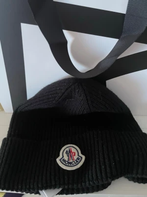 Moncler mössa  - Hej! Säljer en moncler mössa i nyskick. Nypris: 2299 mitt pris: 1199