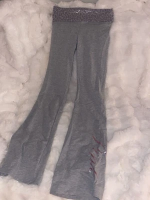 Yogapants PINK, Victoria’s Secret  - Mysiga grå yogapants från PINK med utsvängda ben och bred midjeresår i leopardmönster med glittrig detalj. Byxbenet har en rosa metallictext. Perfekta för chill dagar hemma. Endast använda en gång. Dessa säljs inte på hemsidan längre men är köpta för 650kr💓💓💓💓💓
