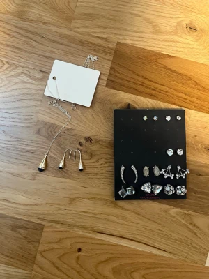Mixade silvriga örhängen med stenar och halsband - Säljer oanvända smycken. Nio par örhängen på en bricka som inte tagits bort och matchande örhängen och halsband som har prislapp kvar