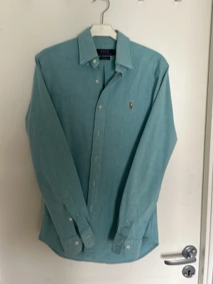 Turkos skjorta från Polo Ralph Lauren - Slimfit turkos skjorta från Polo Ralph Lauren med knappslå och broderad logga på bröstet. Snygg inför sommaren och sitter på riktigt snyggt. Perfekt till jeans eller chinos för en clean look.