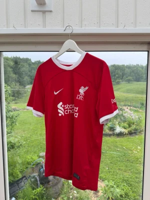 Liverpool FC röd matchtröja Nike - Säljer en röd Liverpool FC matchtröja från Nike med vita detaljer vid krage och ärmslut. Tröjan har klubbmärke och sponsortryck på bröstet samt diskret 97-tryck i nacken. Tillverkad i lätt och ventilerande funktionsmaterial, perfekt för fotboll eller träning. Nyskick