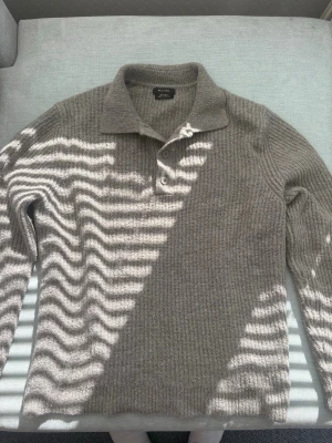 Grå stickad tröja med krage Massimo Dutti - Snygg grå stickad tröja från Massimo Dutti med klassisk krage och två knappar vid halsen. Tröjan har lång ärm och är ribbstickad för en extra mysig känsla. Perfekt för dig som gillar stilrena och tidlösa plagg.