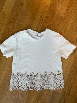 Vit t-shirt med spetskant - Säljer en vit t-shirt från hm med spets nertill❤️ säljer då den inte kommer till användning 