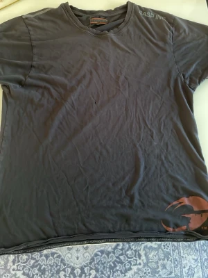 En svart Gasp tshirt - En mörkgrå t-shirt från GASP INC i storlek M. T- shirten har ett tryck i hörnet och materialet är väldigt mjukt. Perfekt för en avslappnad stil. Och jättebra för gymmet.