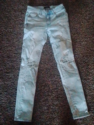 Amiri jeans MX1 size 30 Ljusa slitna skinny jeans - Säljer ett par ljusblå skinny jeans med slitningar och hål på knäna. Jeansen har klassisk femficksmodell och hög midja. Perfekta för dig som gillar en avslappnad och trendig stil. Materialet är denim med stretch för extra komfort.