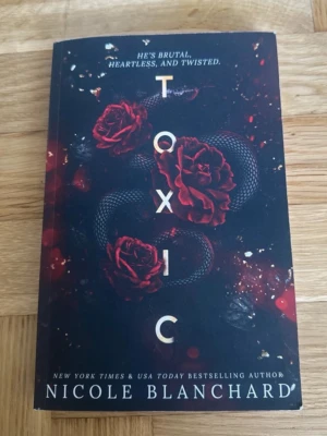 Toxic av Nicole Blanchard - En mörk och intensiv pocketbok med titeln 'Toxic' av Nicole Blanchard. Omslaget är svart med röda rosor och en orm, vilket ger en dramatisk och mystisk känsla. Boken handlar om förbjuden kärlek, besatthet och farliga relationer. Perfekt för dig som gillar spännande och känsloladdad skönlitteratur.