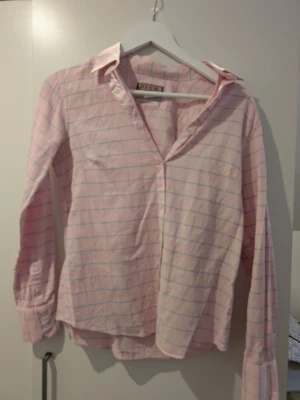 Rutig rosa skjorta från Thomas Pink - Säljer en klassisk rosa skjorta från Thomas Pink med tunna blå rutor. Skjortan är tillverkad i 100% bomull och har lång ärm, krage och knappar framtill. Perfekt för dig som gillar stilrena och tidlösa plagg. 100% bomull 