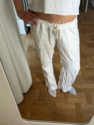 Vita linnebyxor  - Säljer ett par vita linnebyxor med avslappnad passform och dragsko i midjan. Byxorna har raka ben och är tillverkade i ett lätt och luftigt linnematerial, perfekta för varma dagar. Inga synliga loggor eller märken. Ps det är några små hål mellan bena. Men det går lätt att fixa darför säljer jag rätt så biligt 