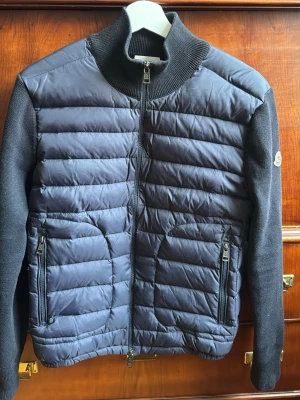 Moncler Cardigan - Säljer min cardigan då den inte kommer till användning längre! Finns ett hål i armhålan från förra ägaren som går att se på 3 bilden men inget som syns när den är på (går nog lätt att sy ihop). Annars är den i riktigt fint skick! Säljs rätt billigt för vill bli av med den. OBS! Sista bilden är ej min utan förra ägarens men fick inte med de sakerna.