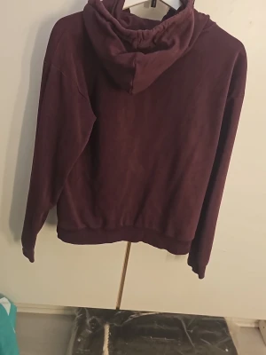 Mörklila hoodie med huva - En enkel och snygg mörklila hoodie från George. Hoodien har en klassisk huva och ribbade muddar vid ärmar och nederkant. Tillverkad i mjukt bomullsmaterial som känns skönt mot huden. Perfekt för dig som gillar en avslappnad och stilren look. Ganska sliten, men funkar som vanlig, Ena snöret att tappat en grej som ni ser där på bilden, men det märken man inte, och om man tänker på det så kan man plocka bort den andra grejen på den andra snöret som ser snörena likadana ut