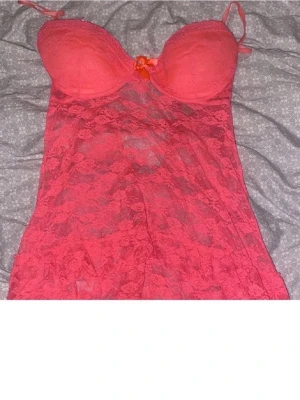 Två rosa klänningar i olika stilar - Säljer två rosa klänningar. Den ena är en spetsklänning med tunna axelband och rosett framtill, transparent och figurnära. Den andra är en enkel, enfärgad klänning med oneshoulder och dekorativ kant upptill. Perfekta för dig som vill sticka ut.