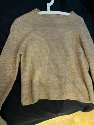 Beige/rosa stickad tröja  - Mysig beige stickad tröja med rund halsringning och långa ärmar. Tröjan har en enkel, rak passform och är tillverkad i ett mjukt, ribbstickat material som passar perfekt till kalla dagar.