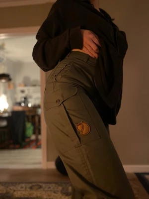 Fjällräven vandringsbyxor vintage - Vintage Fjällräven gråa vandringsbyxor. Byxorna har raka ben, flera praktiska fickor och är tillverkade i slitstarkt material som passar perfekt för en aktiv vardag. Midja: 31,5cm, Innerbenslängd: 84cm. Fint skick, aldrig använda av mig. Går mycket bra att sy upp.