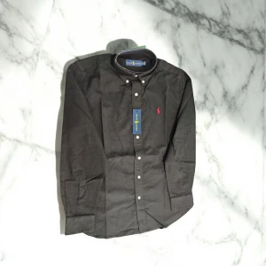 Svart Polo Ralph Lauren Skjorta - Svart Polo Skjorta med röd logga. Storlek XS. Helt ny oanvänd.