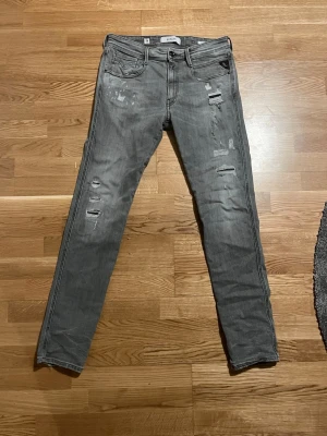 Grå slitna skinny jeans från replay - Säljer ett par grå skinny jeans från Only med slitningar och distressed detaljer på både fram- och baksida. Jeansen har klassisk femficksmodell och normal midja. Perfekta för en avslappnad och trendig look.