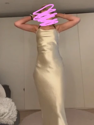 Champagnefärgad sidenklänning - Säljer min champagne färgade balklänning i siden med smala axelband och en vacker drapering framtill. Klänningen har en öppen rygg med snörning som ger en fin detalj. Går att spänna mer i ryggen om man vill.