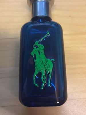 Ralph Lauren Big Pony 1 Herrparfym - En snygg parfymflaska från Ralph Lauren Big Pony Collection, nummer 1. Flaskan är djupblå med en stor gul etta på baksidan och en grön polospelare på framsidan. Metallock i silverfärg ger en exklusiv känsla. Perfekt för dig som gillar sportig och fräsch doft. Sprutar lite hårt men funkar man får inte ont 