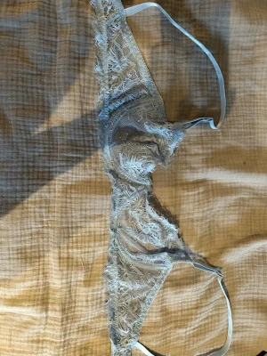 Ljusblå spets-bh  - Säljer en ljusblå bh i transparent spets med blommigt mönster. Bh:n har tunna axelband och mjuka kupor utan vaddering. Materialet är en blandning av polyamid och elastan för en bekväm och stretchig passform. Aldrig använd 