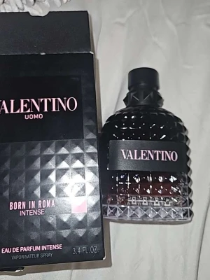 Valentino Uomo Born In Roma Intense - Valentino Uomo Born In Roma Intense är en lyxig parfym med en mörk, elegant flaska i svart och transparent glas med nitar. Doften kommer i en stilren förpackning med rosa och vita detaljer. Perfekt för dig som vill ha en exklusiv och modern signaturdoft.