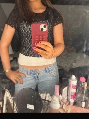 Svart spetsblus - Säljer en svart, genomskinlig spetsblus med korta ärmar. Blusen har ett snyggt spetsmönster och är croppad i modellen, perfekt att styla över ett linne eller som den är. Superfin och i helt nytt skick!🥰 storlek m men skulle säga att den är som xs