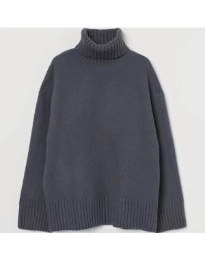 Mörkgrå polotröja i stickat - Oversized mörkgrå stickad polotröja med bred ribbstickning vid krage, ärmslut och nederkant. Tröjan har en hög, vikt krage och långa ärmar. Perfekt för lager på lager och en chill look.