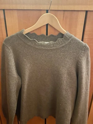 Brun stickad tröja - Grön stickad tröja med lång ärm och volangkant vid halsringning, ärmslut och nederkant