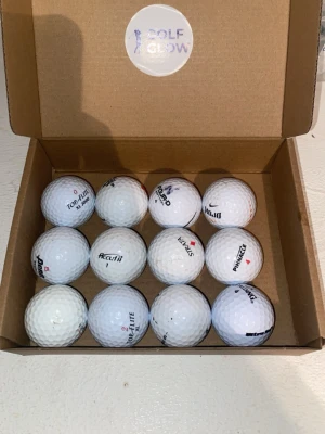 Florida bollar 12-pack - Säljer en låda med tolv vita golfbollar från olika märken som Top Flite, Pinnacle, Nike och Acuity. Bollarna levereras i en brun kartong med Golf Glow-logga på insidan av locket. Perfekt för dig som vill fylla på golfväskan.