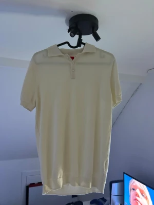 Vit pikétröja med kort ärm ryvls  - Klassisk vit pikétröja med krage och knappar framtill. Tröjan har korta ärmar och ribbade muddar vid ärmslut och nederkant. Perfekt till en clean och enkel stil.