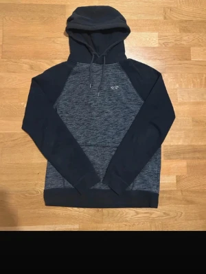 Two-tone hoodie från Hollister - Snygg two-tine hoodie från Hollister med kontrasterande ärmar och huva. Framsidan har en liten Hollister-logga på bröstet. Tillverkad i mjukt material och har en klassisk känguruficka framtill. Perfekt för en avslappnad och stilren look.