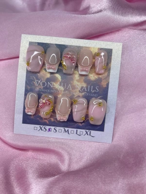 LoveCore (S);Short Ballerina - Handgjorda press-on naglar i rosa och nude toner med 3D rosetter, pärlor och guldfärgade detaljer. Naglarna har en kort, ballerina form och en glansig finish. Perfekt för dig som vill ha en söt och unik nageldesign.S: 15 mm, 11,5 mm, 12 mm, 11 mm, 9 mm 