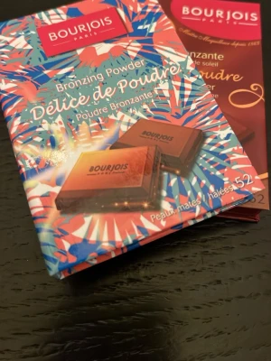 Bourjois Délice de Poudre Bronzer x2 - Säljer Bourjois Délice de Poudre Bronzing Powder, en pressad bronzer i puderform. Förpackningen är färgglad och kompakt, med motiv i brunt, blått och orange. Produkten ger en solkysst look och passar för matta hudtoner. Perfekt för att framhäva ansiktets konturer.