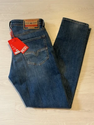 Diesel jeans - Helt nya jeans från diesel med en snygg tvättad blå färg. Jeansen är som sagt aldrig använda och har fortfarande lappar kvar. Byxorna är en model som sitter ganska slim men rakt. De är storlek 28/32