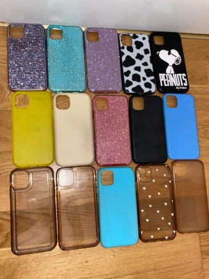 Färgglada mobilskal i olika mönster - Säljer ett gäng mobilskal i olika färger och stilar, bland annat glitter, genomskinliga, enfärgade och ett svartvitt Peanuts-motiv. Skal i blått, gult, lila, rosa, svart, beige och brunt. Materialen varierar mellan plast och silikon. Perfekt för dig som vill byta stil på mobilen ofta! Alla 15st 170kr Iphone 11