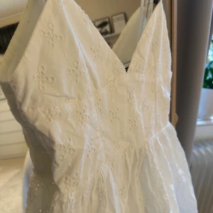 Vit broderad sommarklänning från Zara - Söt vit klänning med broderade blommor och v-ringad. Klänningen är ärmlös med smala axelband och har en lätt utställd kjol. Perfekt för varma dagar och somriga tillfällen. Från Zara. Superfin och går inte att få tag i längre. 