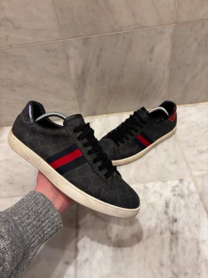Svarta Gucci Ace - Svarta Gucci ace. Storlek: 45. Skick: 7,5/10, bedöm själv. Nypris: 7000kr, mitt pris 1999kr. Har ej skolåda. Fraktar inom 24 timmar. Fråga på!