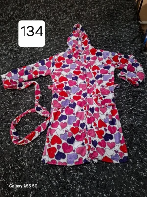 Färgglad morgonrock med hjärtan - Mysig morgonrock i mjuk fleece med färgglatt hjärtmönster i rött, lila, rosa och vitt. Modellen har huva, två stora fickor framtill och ett matchande midjebälte. Perfekt för att chilla hemma och hålla sig varm.