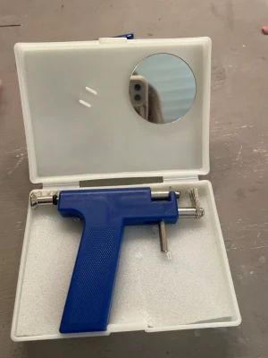 Blå öronhåltagningspistol med tillbehör - Säljer ett kit för öronhåltagning med blå pistol i plast och metall, spegel i locket samt flera örhängen och tillbehör i en vit förvaringslåda. Perfekt för dig som vill ta hål i öronen hemma. Allt du behöver för enkel användning ingår. 70st örhängen 