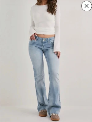 Ljusblå Low waist jeans Pull&bear - Säljer ett par ljusblå bootcut jeans från Pull&bear i storlek 34. Jeansen har låg midja, klassisk femficksmodell och raka, lätt utsvängda ben. 